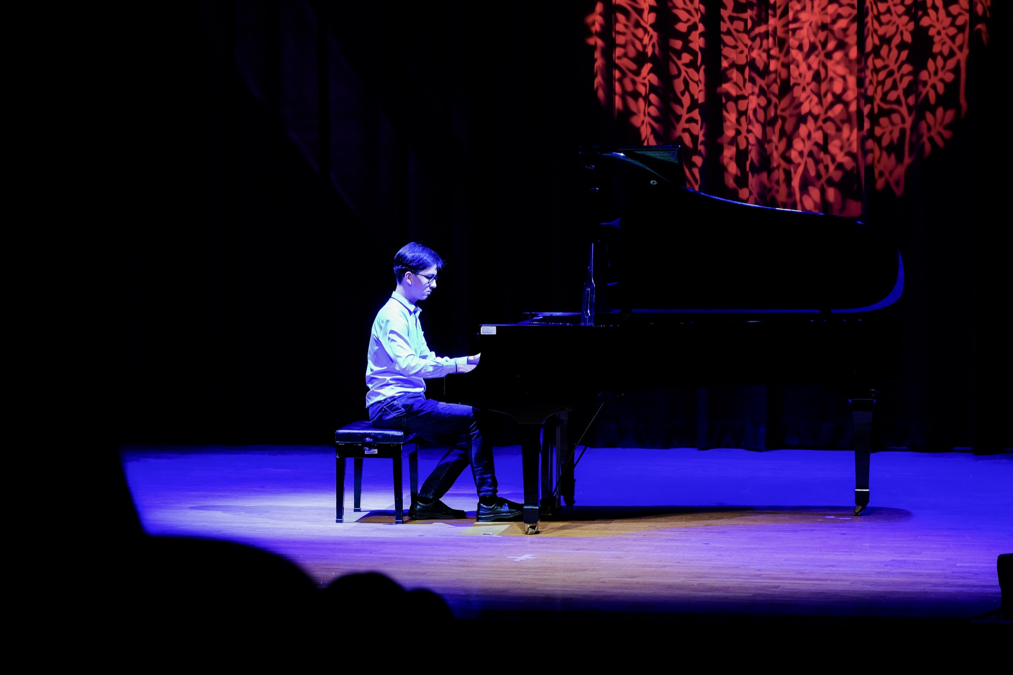 Andrew Huang seated at a grand piano during a recital